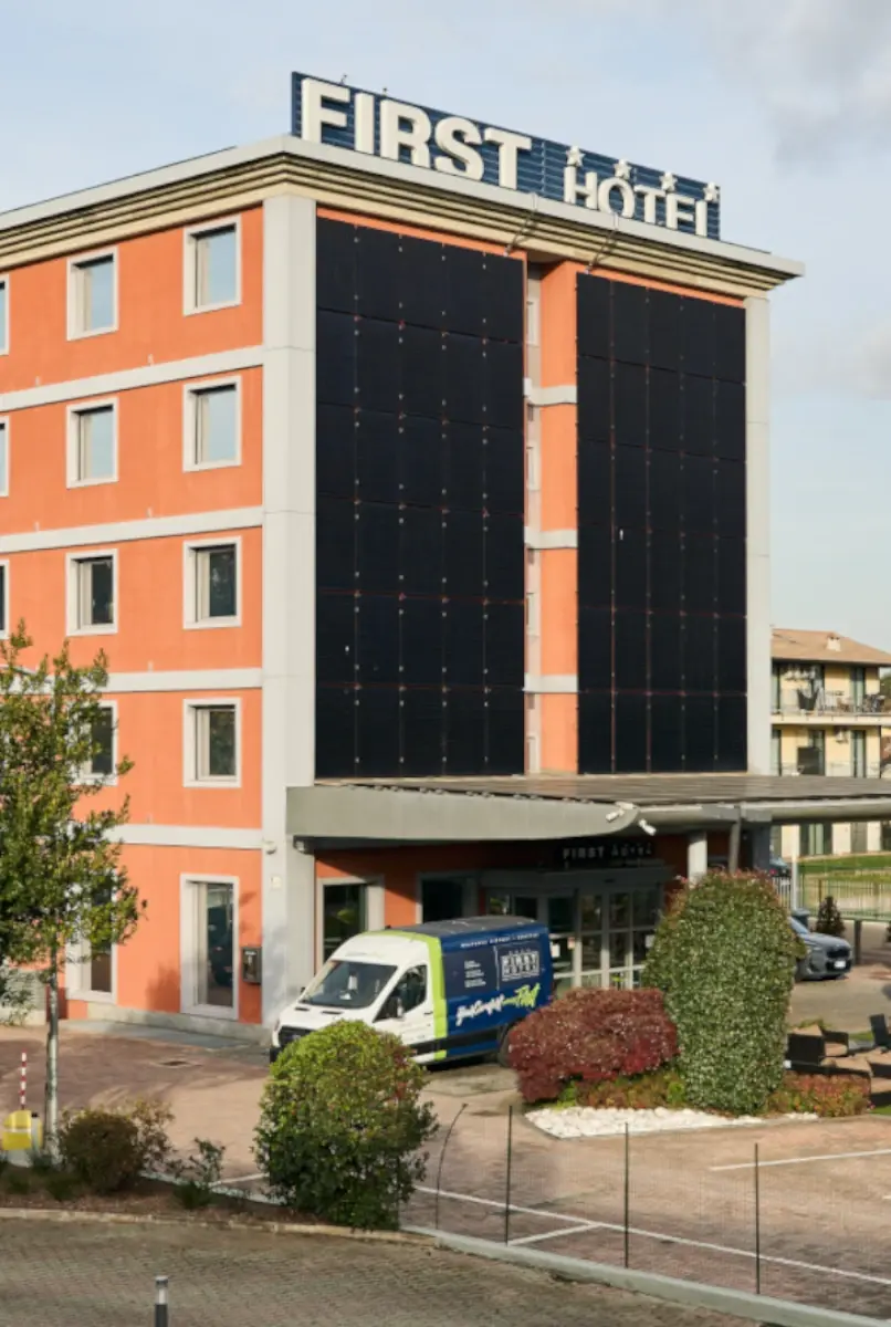 La facciata del First Hotel con l’insegna in cima e la navetta parcheggiata davanti all’ingresso