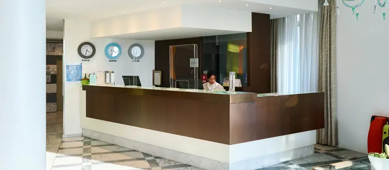 Il bancone della reception in legno scuro, con gli orologi alla parete